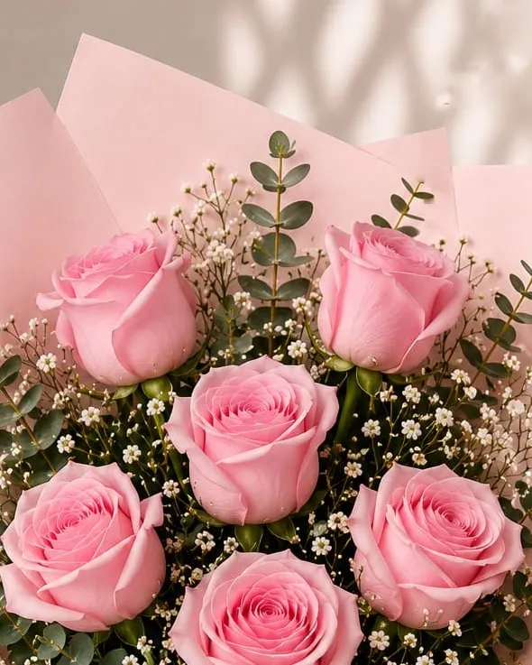 Detalle: ramo de seis rosas rosadas con paniculata y eucalipto en papel rosado con cinta rosada