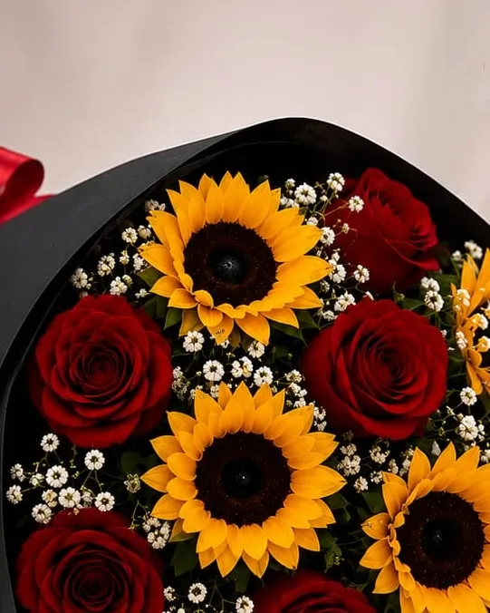Detalle: ramo de brazo de rosas rojas y girasoles con paniculata en envoltura negra con cinta roja