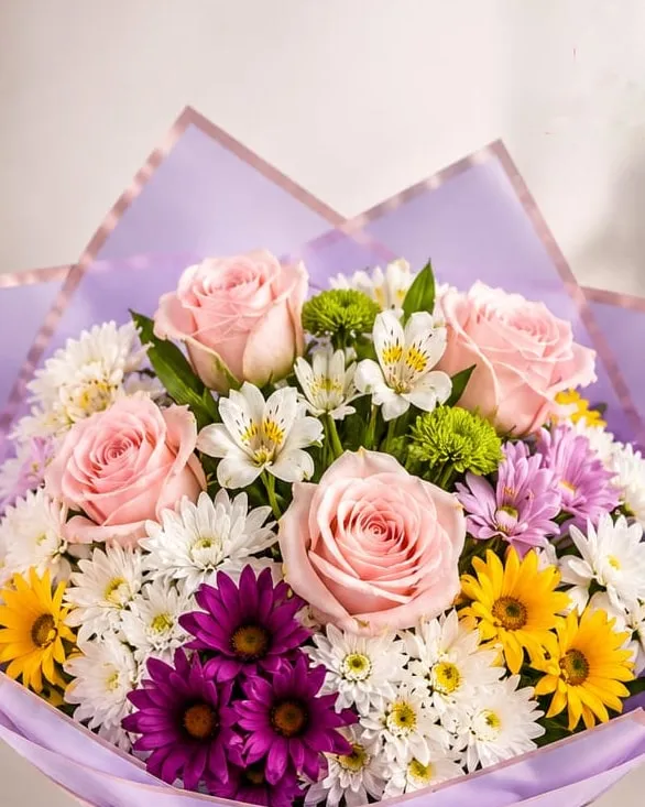 Detalle: ramo de rosas rosadas, margaritas y crisantemos en papel lila con cinta durazno