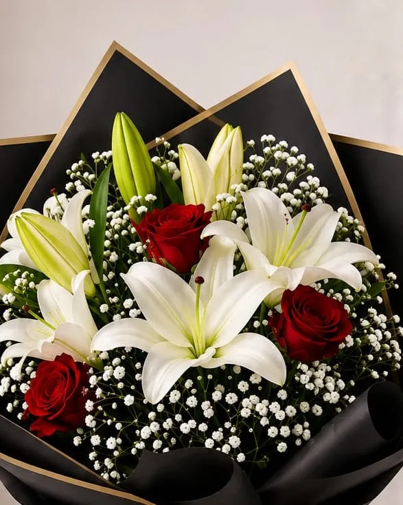 Detalle: ramo de rosas rojas y lilium blancos con paniculata en papel negro con cinta dorada